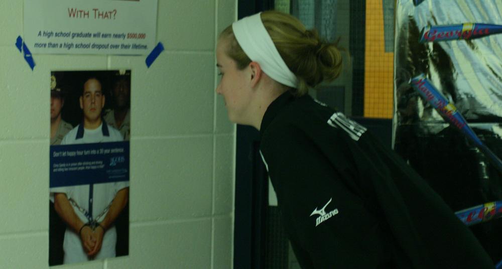 Jenny Tomasello looks at the poster that hangs on the wall outside Coach Mark Williamson's door. It previously hung outside the attendance office for many years.Tomasello now fully understands the meaning behind the poster after hearing Sandy's story.