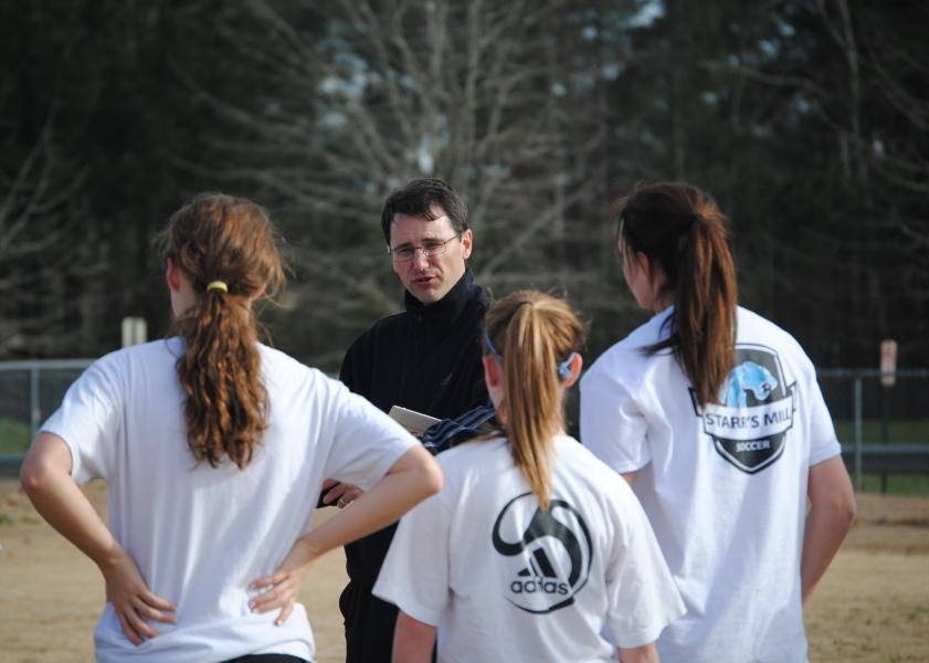 At practice, head girls' varsity coach John Bowen fills the girls in on some strategies for certain plays.