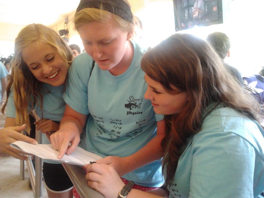 Juniors Claire Williams (left), Ashley Powers (middle), and Tori Melton check on their work packet before riding on the Acrophobia. 