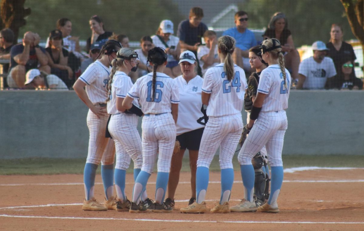 Varsity softball head coach Peyton Dean talks with the team at the pitcher’s circle. The Panthers lost to Central 17-3. 