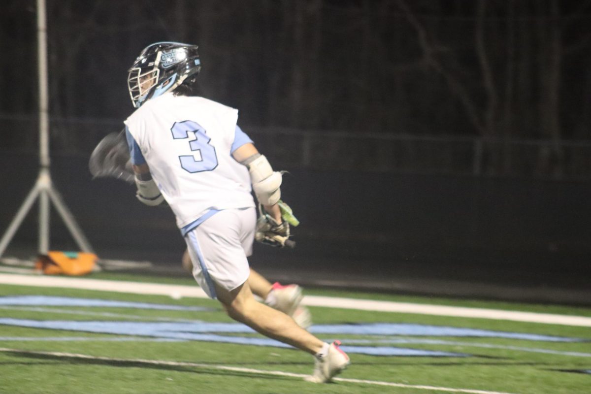 Junior Tanner Via runs across the field with possession of the ball. He set a new school record with nine goals in the team’s 18-7 win over Whitewater.